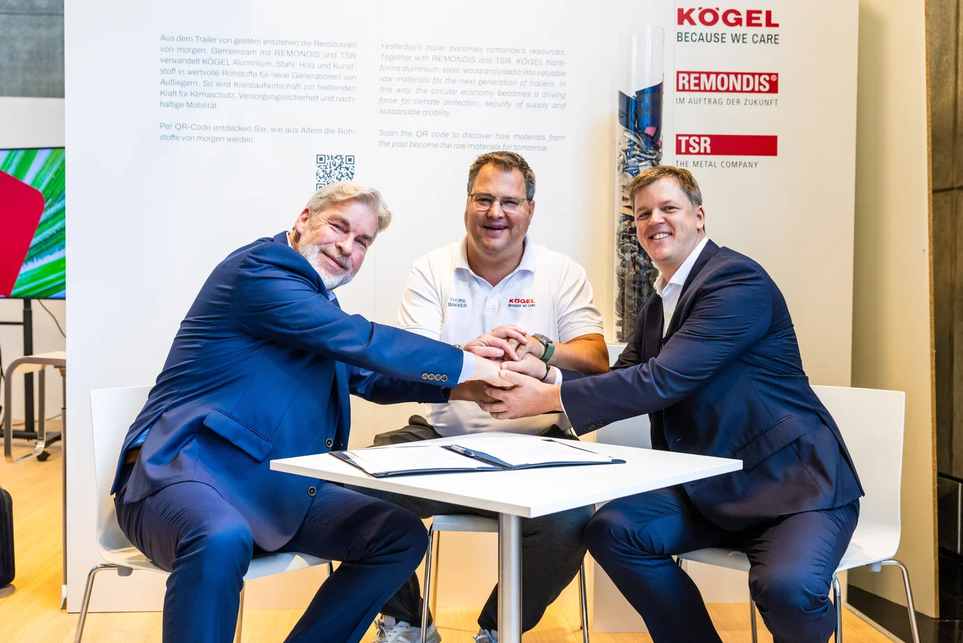 Kögel, TSR und REMONDIS starten Pilotprojekt. Am Tisch sitzend, geben sich die Hände.