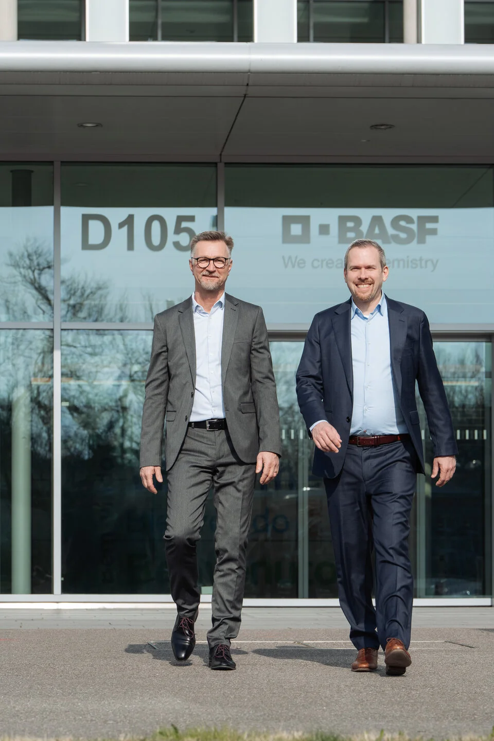 Zwei Männer laufen vor einem Gebäude in dieselbe Richtung