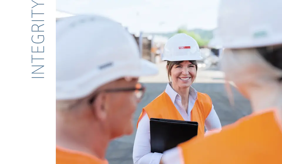  Employee with protective equipment and clipboard explains something to two colleagues