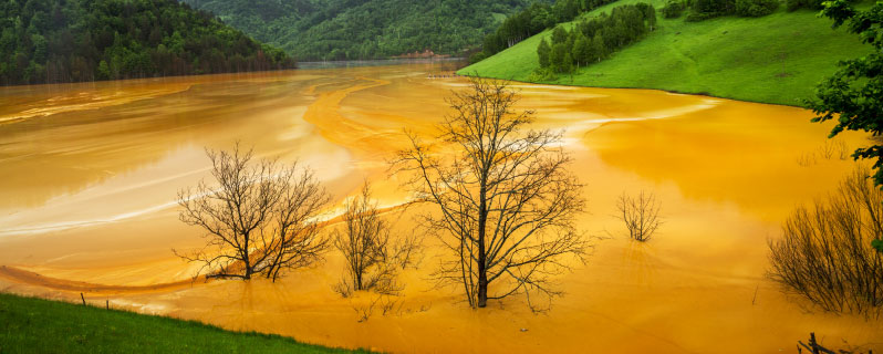 Durch den Abbau von Neodym verseuchtes Feld mit gelbem, vergiftetem Wasser 