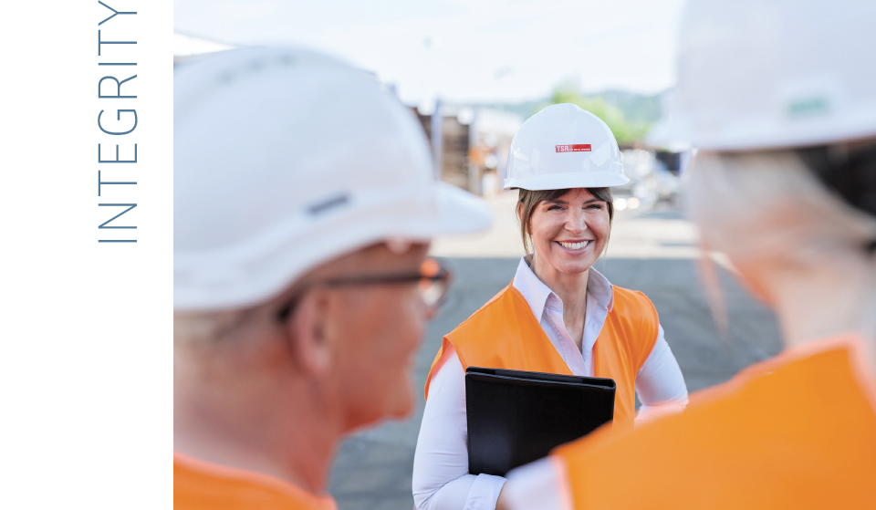  Employee with protective equipment and clipboard explains something to two colleagues